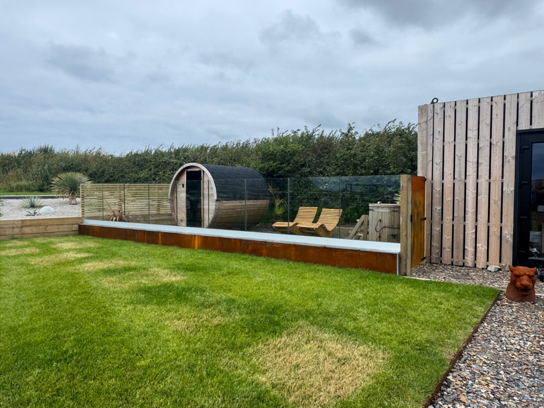 Cedar barrel sauna and ice bath on a glass-balustraded deck overlooking the meadow